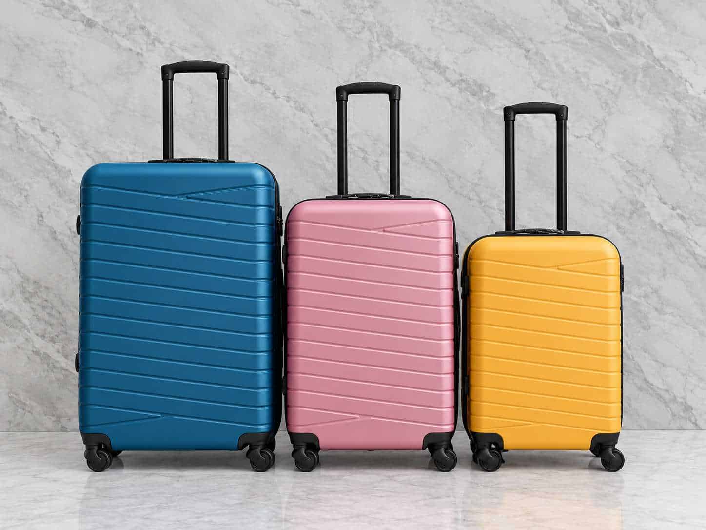 Colorful suitcases in blue, pink, and yellow on marble floor.
